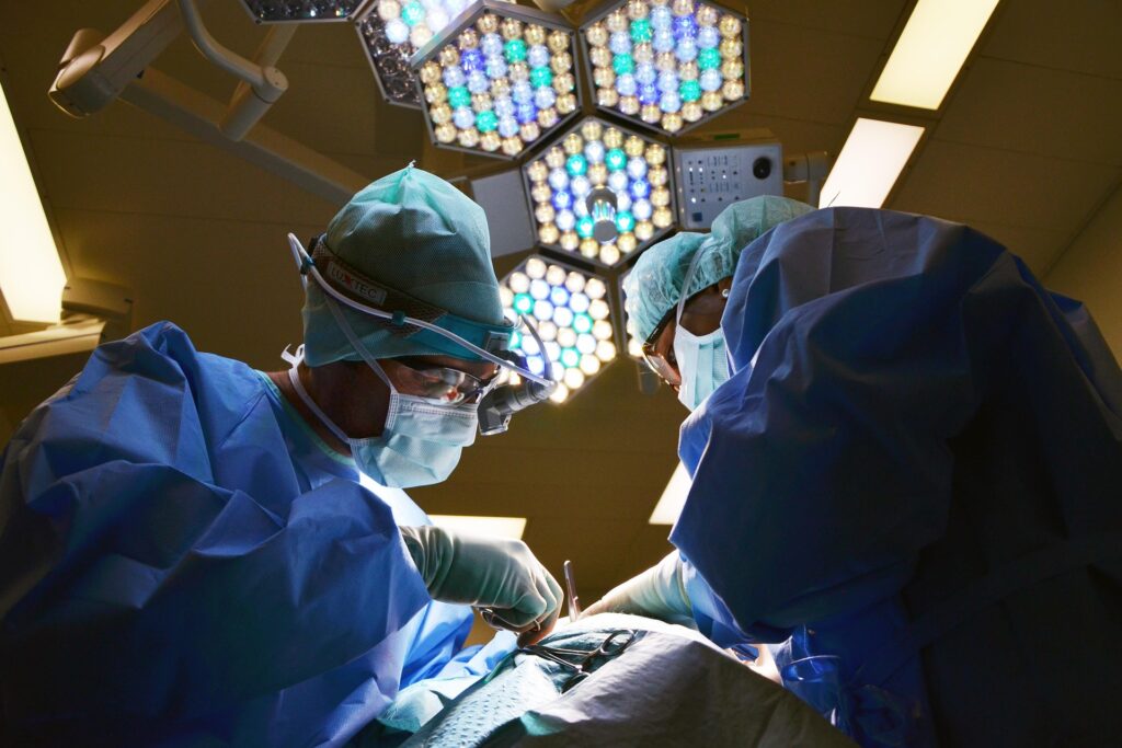 A pair of surgeons operating with a hexagonal lighting fixture above them.