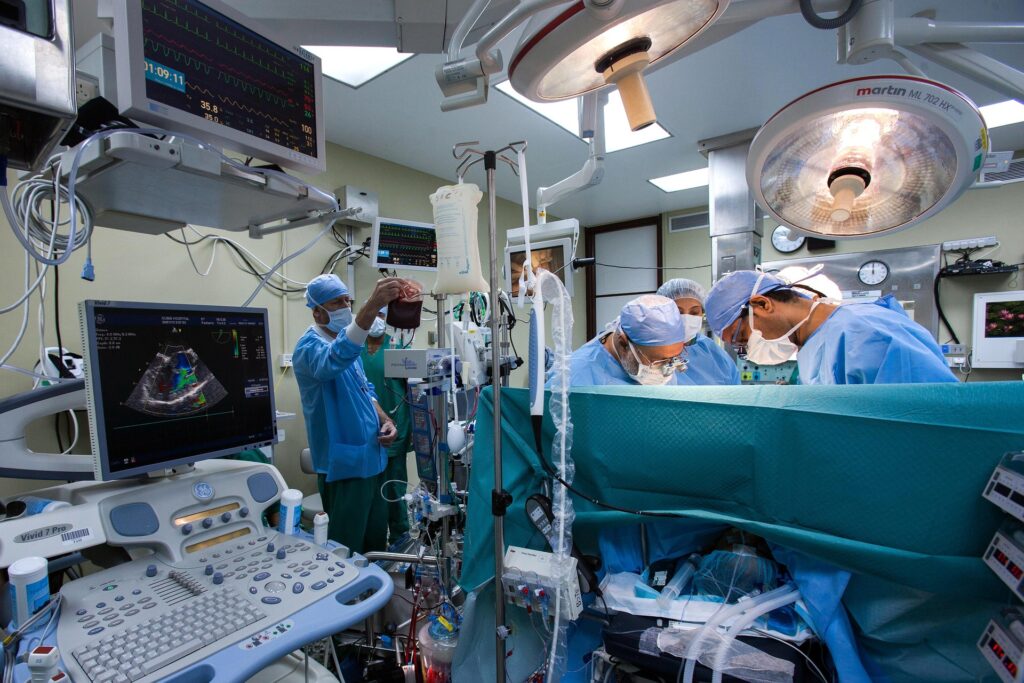 A scene of a surgical procedure, various care providers are wearing masks and other PPE around a patient.